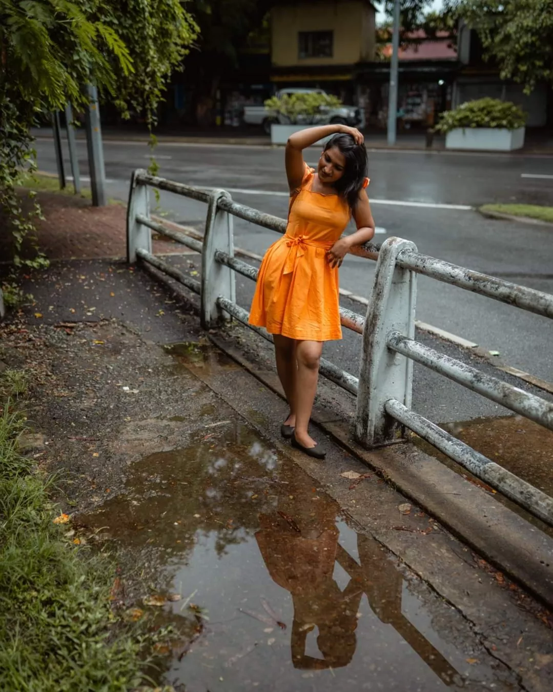 Orange dress fashion editorial photography by a roadside railing in Colombo, Sri Lanka